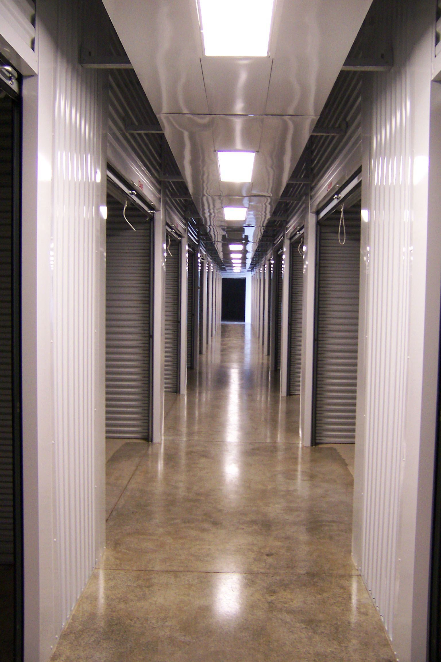 Well-maintained, brightly lit interior hallway of Access Storage's climate-controlled facility with pristine white doors.
